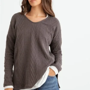Woman wearing a cozy brown sweater with a white shirt underneath.