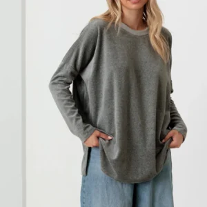 Woman wearing a loose gray sweater and blue jeans.