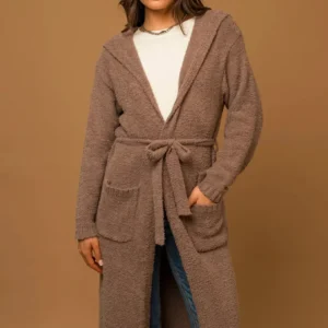 Woman wearing a brown belted cardigan over a white top.