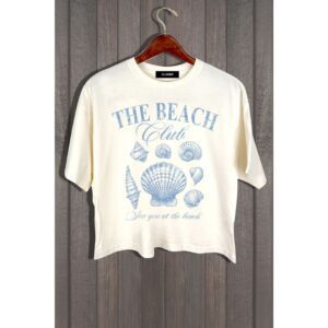 White t-shirt with blue beach-themed print hanging on a wooden hanger.