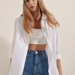 Woman in casual white top and blazer with blue jeans.