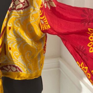 Colorful blouse with vibrant yellow and red patterns and wide sleeves.