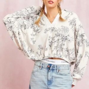 Woman wearing a loose floral print sweater and light blue jeans.