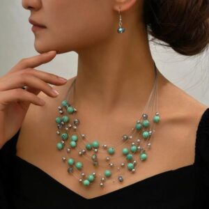 Elegant turquoise and pearl jewelry set worn by a woman.