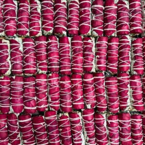Rows of vibrant pink rosebuds tied with white strings.