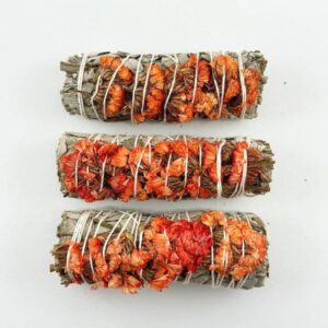 Three bundles of sage wrapped with dried orange flowers on a white background.