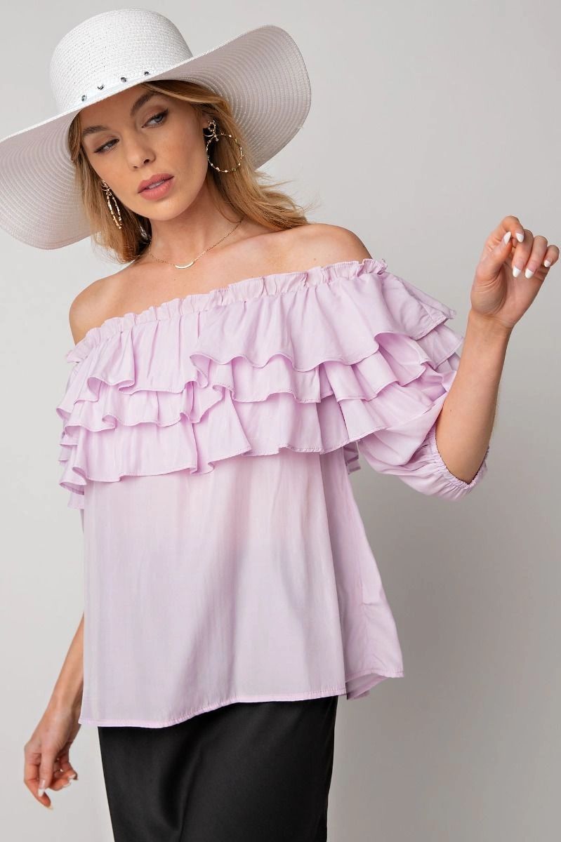 Woman wearing a light pink off-shoulder ruffle blouse.