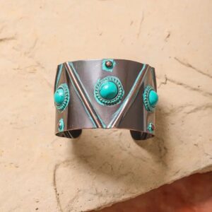 Silver cuff bracelet with turquoise stones and geometric designs.