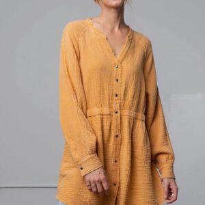Woman wearing a mustard yellow button-down dress with long sleeves.
