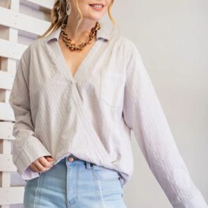 Woman wearing a loose white blouse and light blue jeans.
