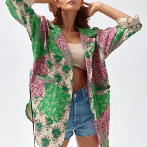 Woman wearing a colorful floral kimono over a crop top and denim shorts.