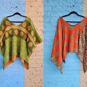 Two colorful knitted ponchos hanging against a brick wall.