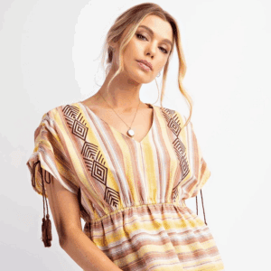 Woman wearing a striped, patterned dress with tassel details on sleeves.