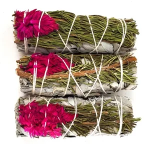 Three bundles of sage wrapped with string and decorated with pink flowers.