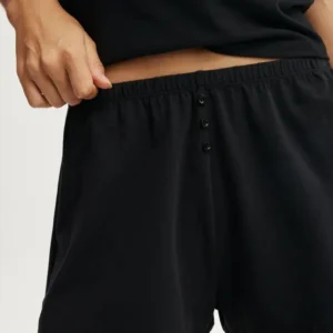 Close-up of black pajama pants with buttoned waistband.