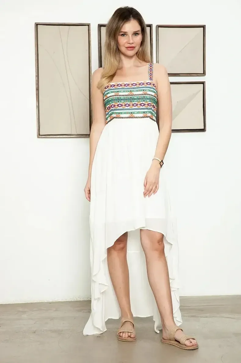 Woman wearing a white high-low dress with a colorful patterned top.