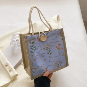 A stylish blue floral handbag with rope handles.
