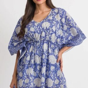 Woman wearing a blue and white floral patterned dress with loose sleeves.