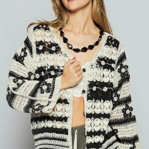 Woman wearing a black and white striped cardigan with a chunky necklace.