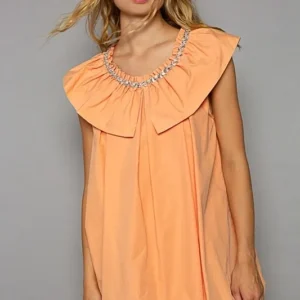 Woman wearing a peach dress with a large ruffled collar.