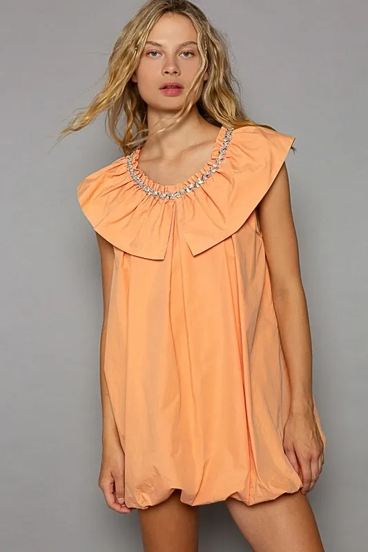 Woman wearing a peach dress with a large ruffled collar.
