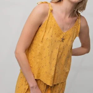 Woman wearing a yellow sleeveless top with floral patterns.