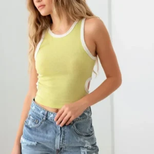 Woman wearing a green and white sleeveless top with denim shorts.