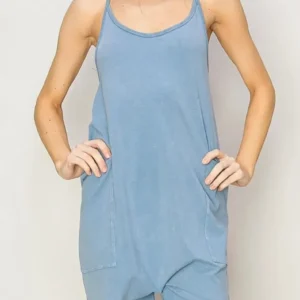 Woman wearing a loose, sleeveless blue dress standing with hands on hips.