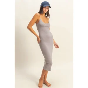 Woman in a fitted gray midi dress and blue cap.