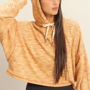 Woman wearing a cozy orange hooded sweater with long sleeves.