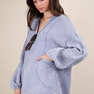 Woman wearing a cozy oversized lavender sweater with front pockets.