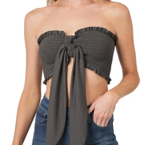 A woman wearing a strapless black crop top with a front tie detail.