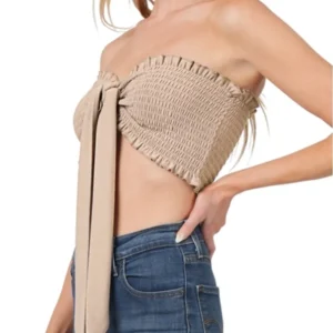 Woman wearing a beige strapless crop top and blue jeans, posing with hand on hip.